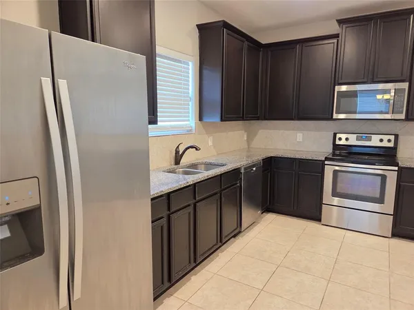 a kitchen with stainless steel appliances granite countertop a refrigerator and a sink