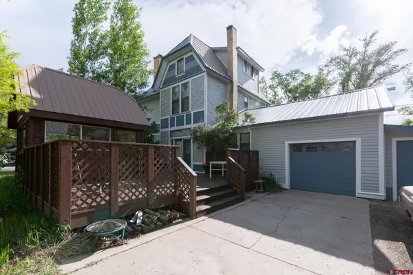 a view of a house with a small yard and a large tree