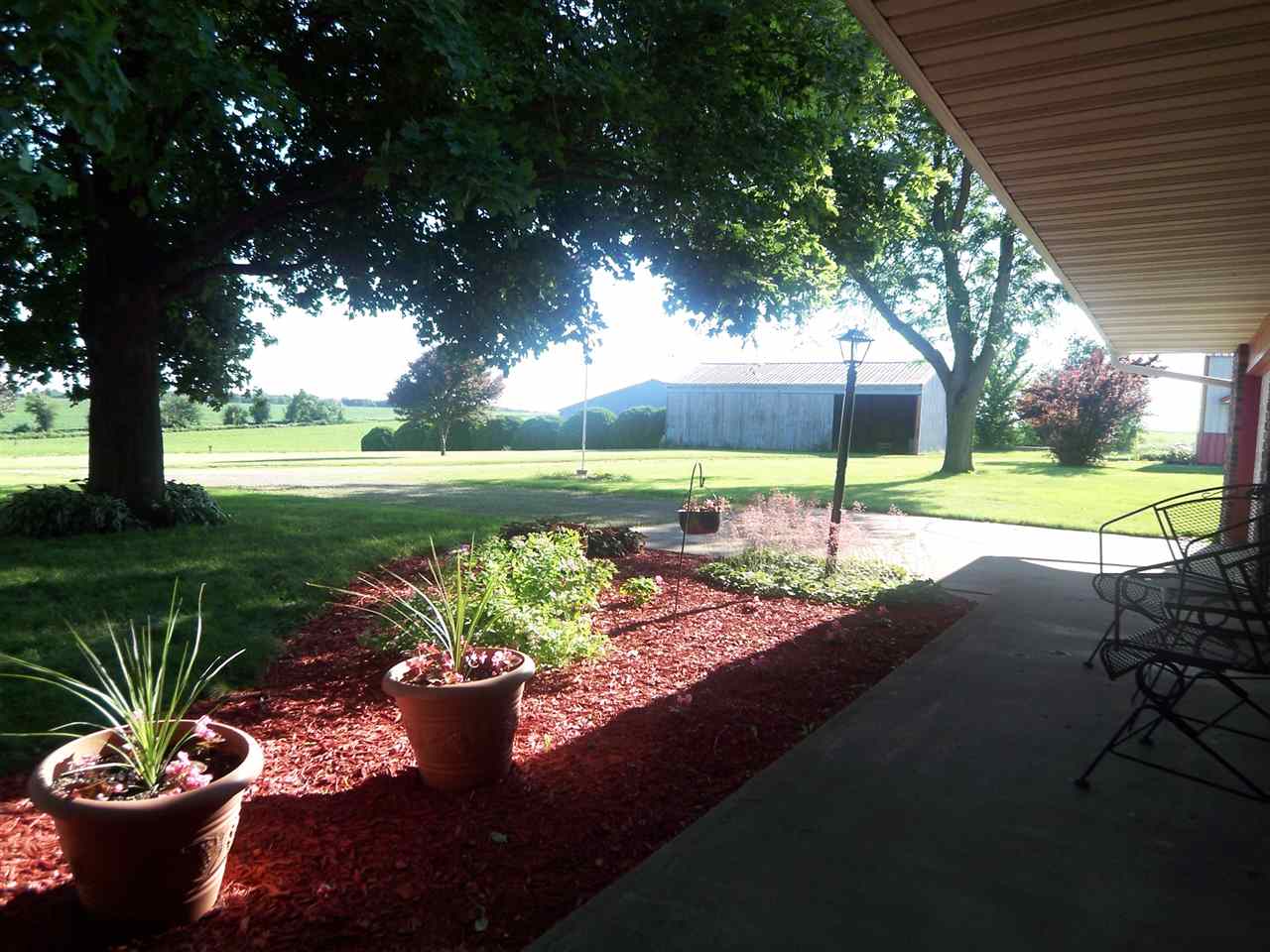 2666 South Rock City Road Ridott, IL 61067 - Photo 4 of 25 a view of a backyard with table and chairs potted plants and large tree