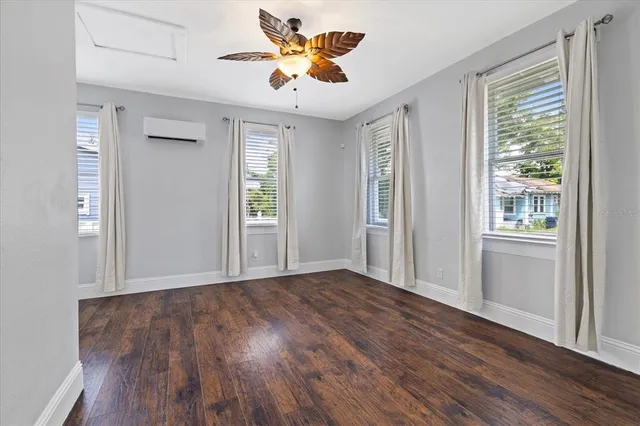 a view of an empty room with window and wooden floor