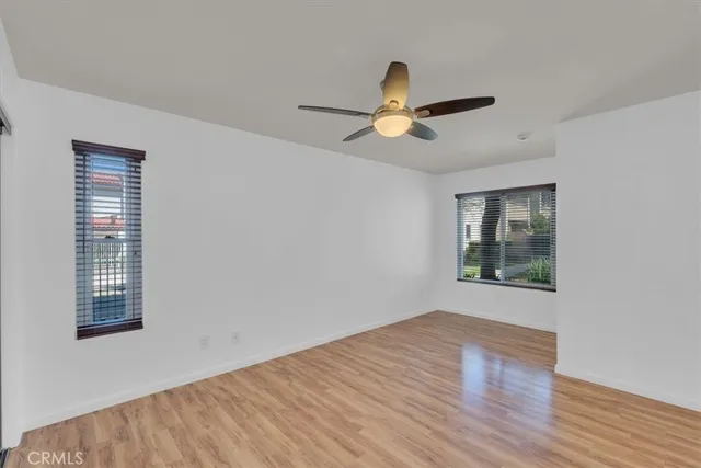 a view of empty room with wooden floor and fan