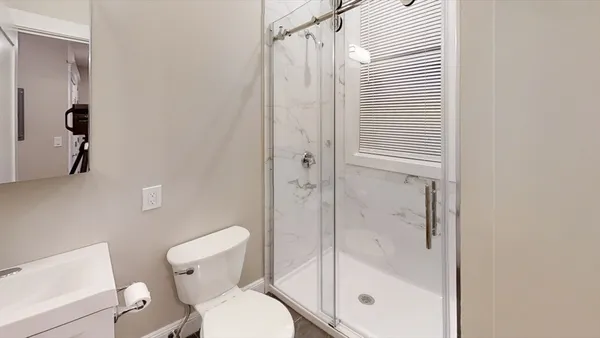 a bathroom with a shower a toilet and a window