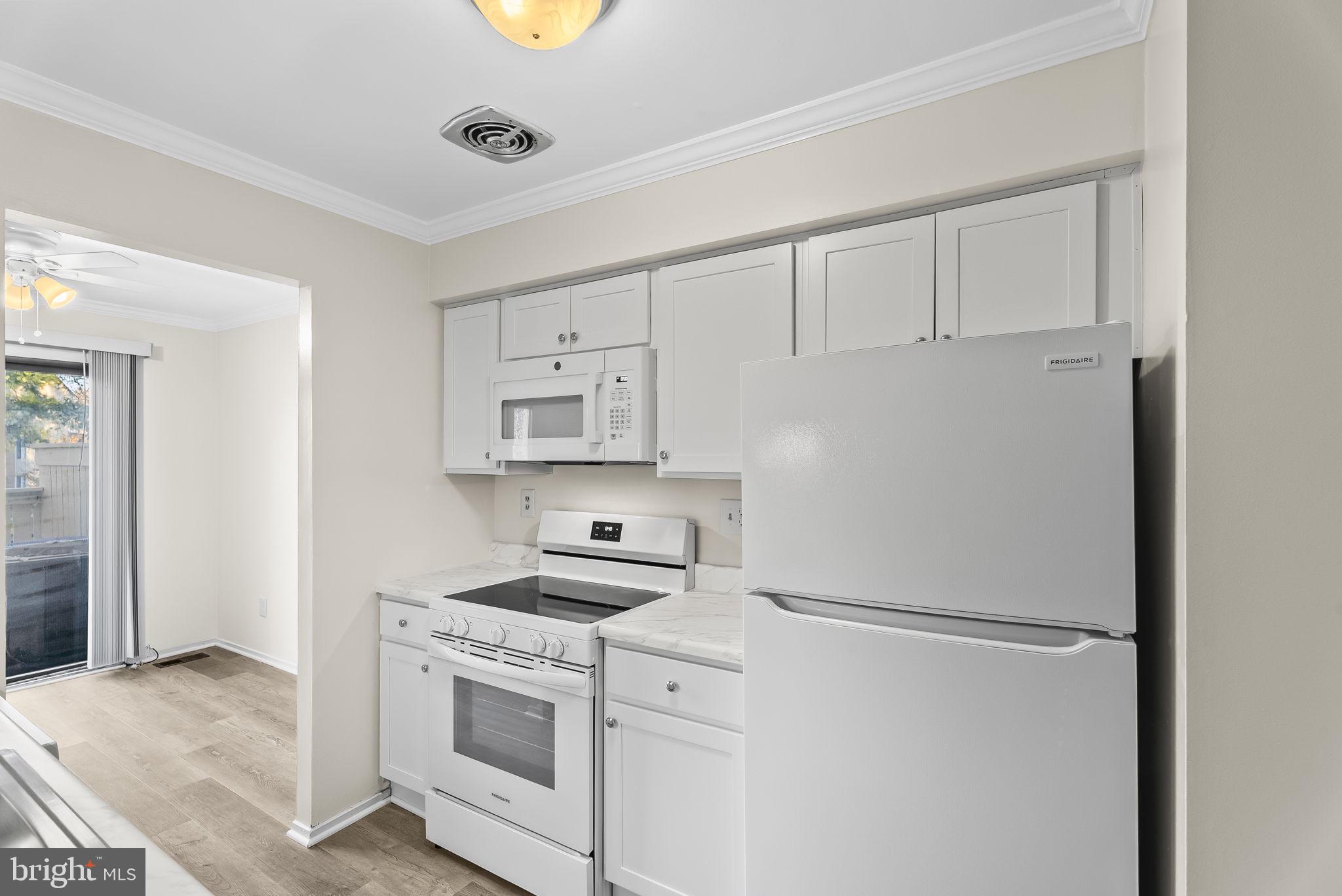 9413 Penshurst Court Gaithersburg, MD 20886 - Photo 15 of 32 a kitchen with white cabinets and white appliances