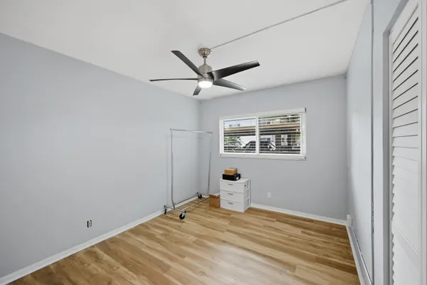 a view of empty room with wooden floor and fan