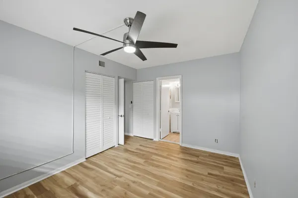 a view of empty room with wooden floor and fan