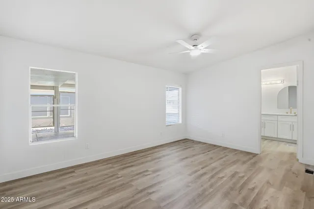 an empty room with wooden floor closet and windows