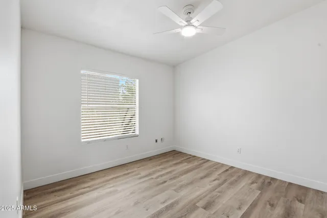 an empty room with a window and a ceiling fan