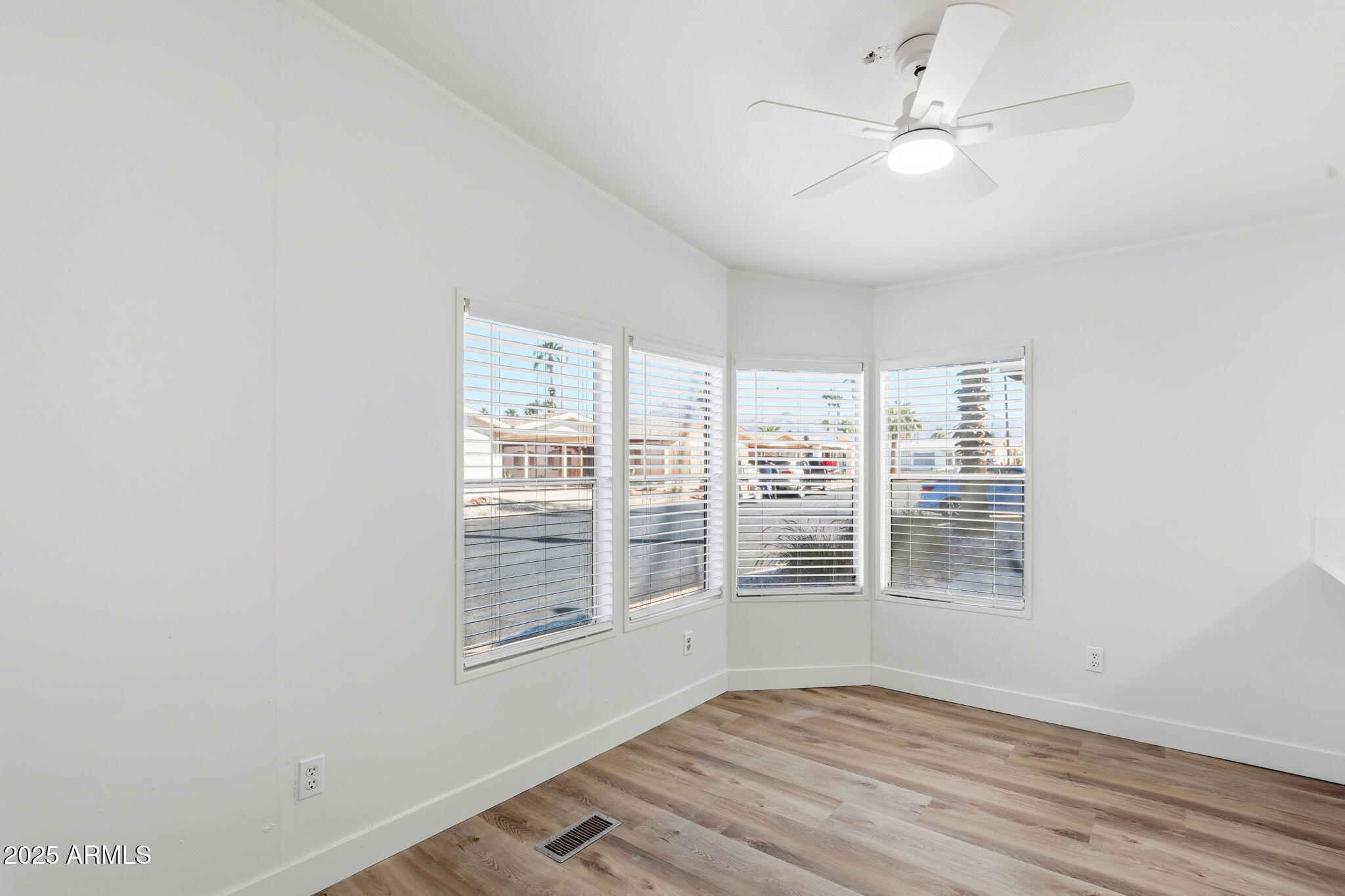 3500 South Tomahawk Road, Unit 142 Apache Junction, AZ 85119 - Photo 10 of 38 an empty room with wooden floor fan and windows