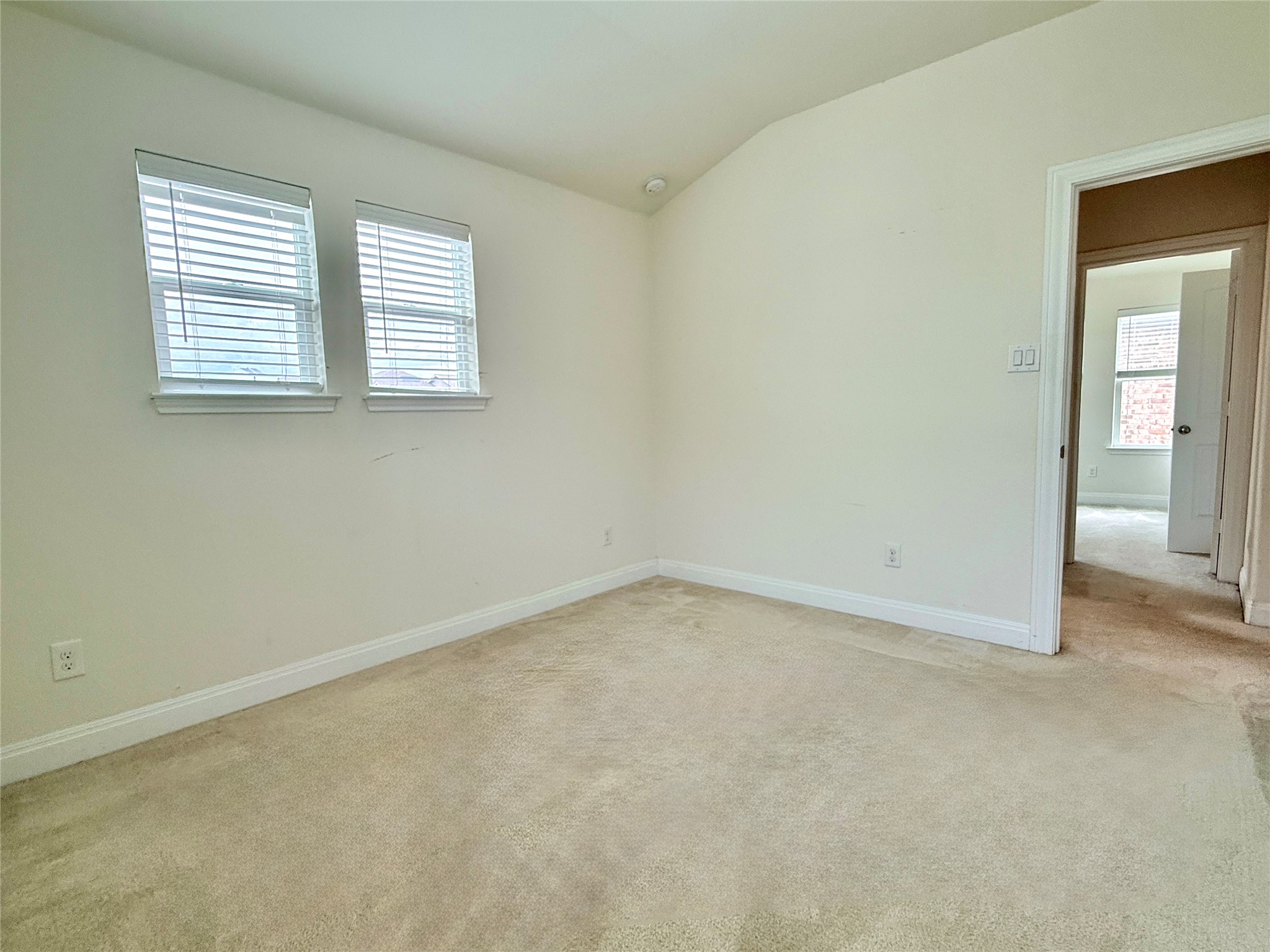 2101 Split Diamond Way, Unit 40 Round Rock, TX 78664 - Photo 30 of 32 A well-lit bedroom features vaulted ceilings and plush carpeting throughout, ready for personalization.