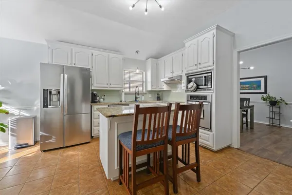 a kitchen with stainless steel appliances a refrigerator a stove a sink a dining table and chairs