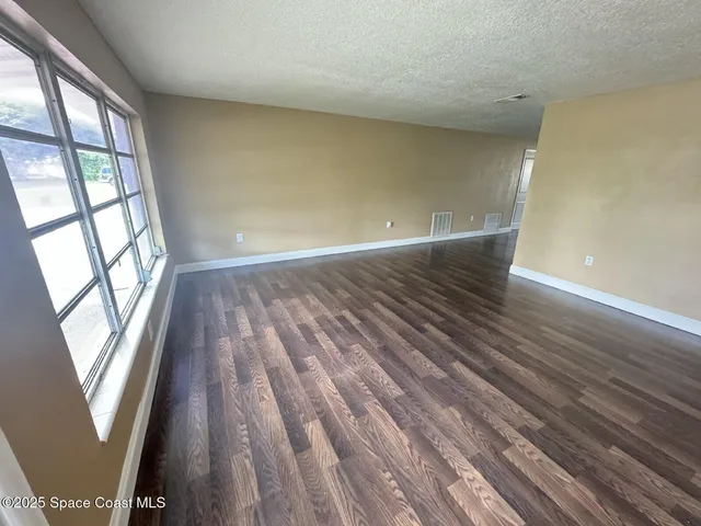 a view of wooden floor in an empty room with a window