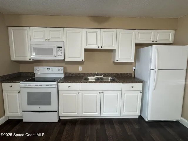 a kitchen with granite countertop white cabinets and white appliances