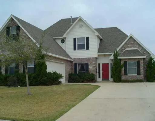 a front view of house with yard and trees in the background