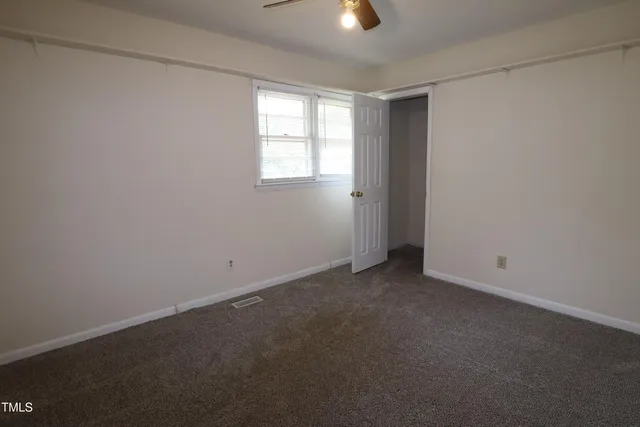 an empty room with a window and closet area