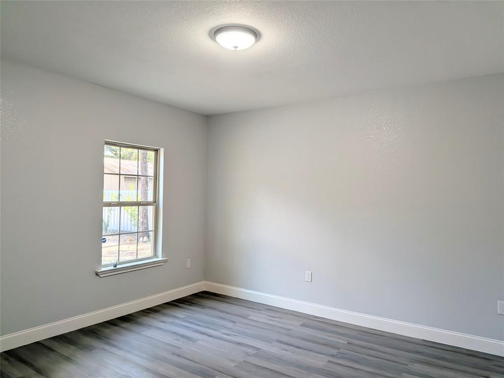 608 Holcomb Road Dallas, TX 75217 - Photo 12 of 23 an empty room with wooden floor and windows