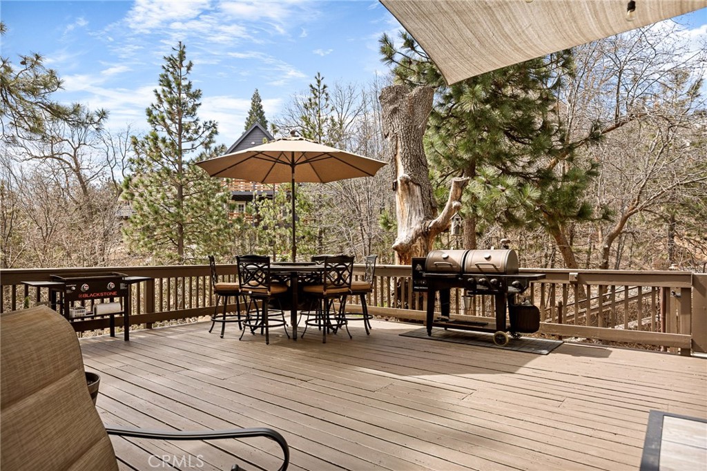 28111 Grenoble Drive Lake Arrowhead, CA 92352 - Photo 10 of 40 a view of a roof deck with table and chairs under an umbrella with wooden floor