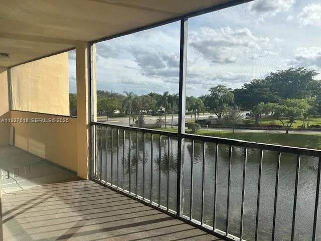 a view of a balcony with wooden floor next to a yard