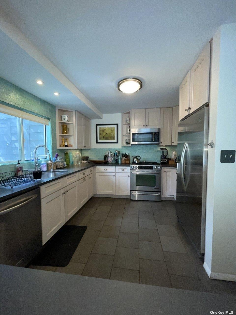 275 Wilmot Road Ocean Beach, NY 11770 - Photo 5 of 19 a kitchen with stainless steel appliances granite countertop a refrigerator a stove a sink and a microwave