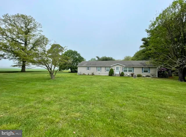 a view of a big house with a big yard and large trees