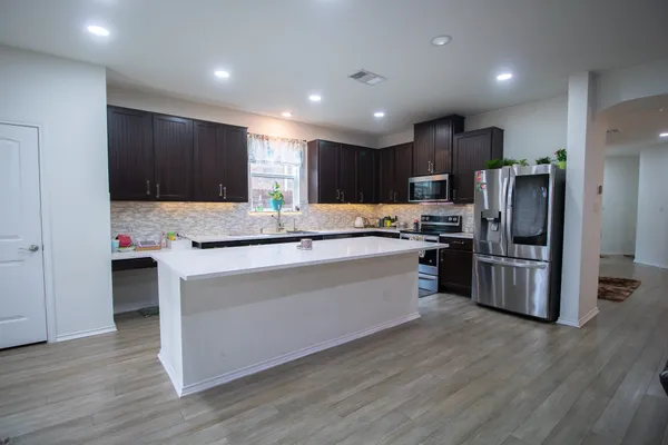 a kitchen with kitchen island stainless steel appliances a refrigerator and a stove top oven