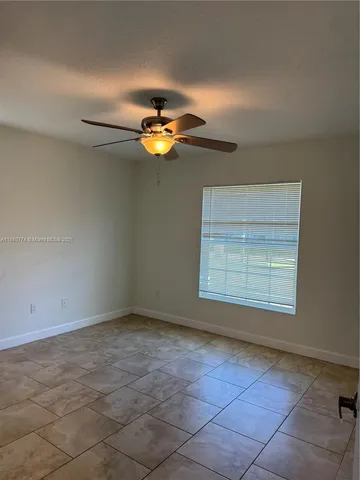 an empty room with a chandelier fan and windows