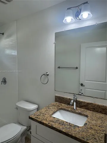 a bathroom with a granite countertop sink a toilet and a mirror