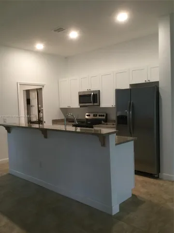 a kitchen with granite countertop a refrigerator and a stove top oven