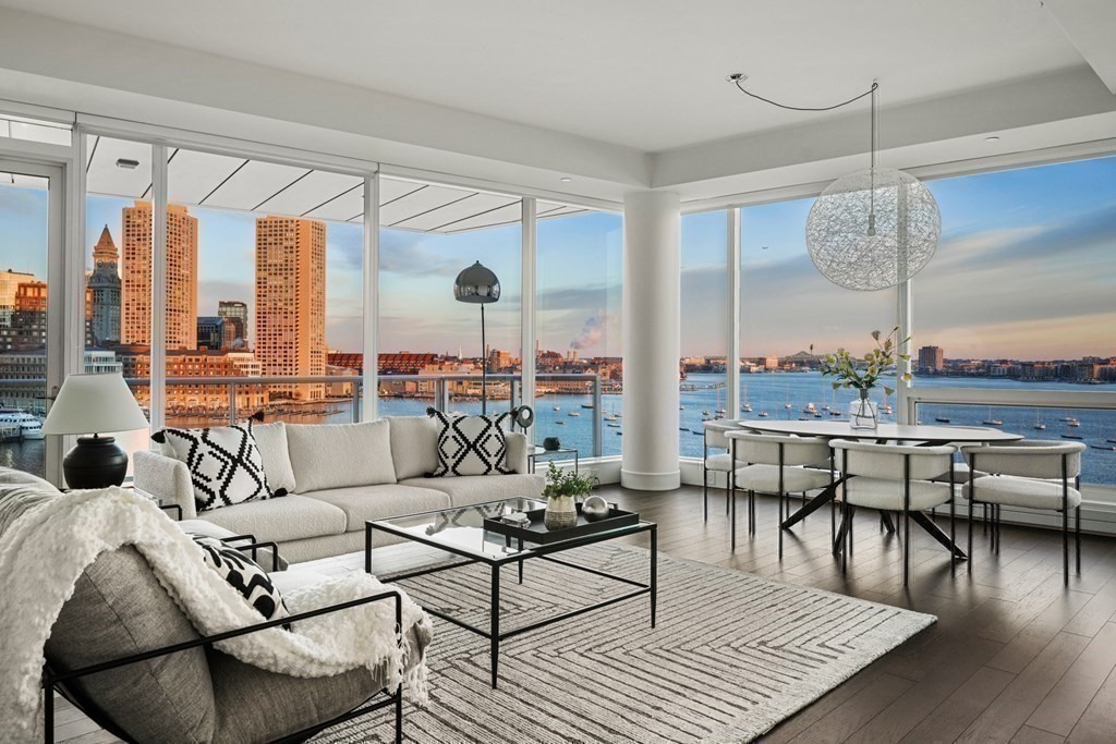 a living room with furniture wooden floor and floor to ceiling windows