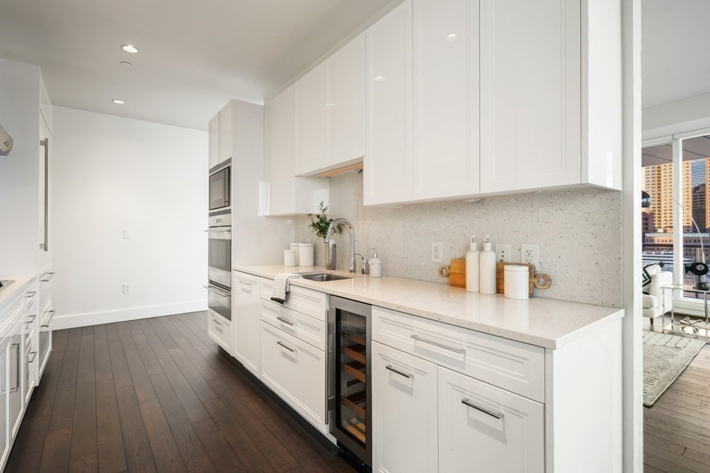 22 Liberty Drive, Unit 7A Boston, MA 02210 - Photo 23 of 31 a kitchen with a sink dishwasher stove and white cabinets with wooden floor