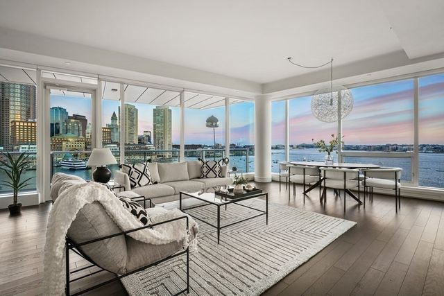 a living room with furniture large windows and wooden floor