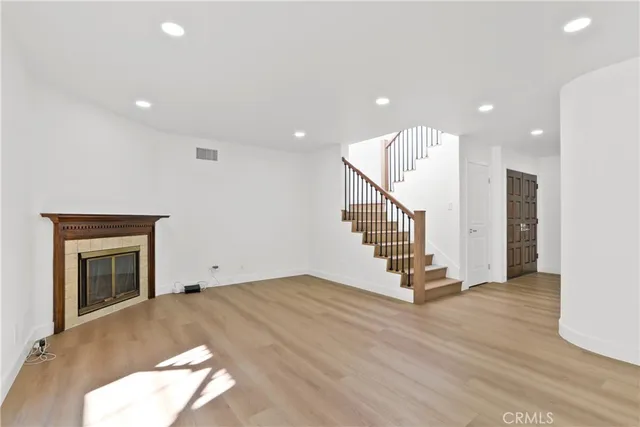 a view of an empty room with wooden floor and a fireplace