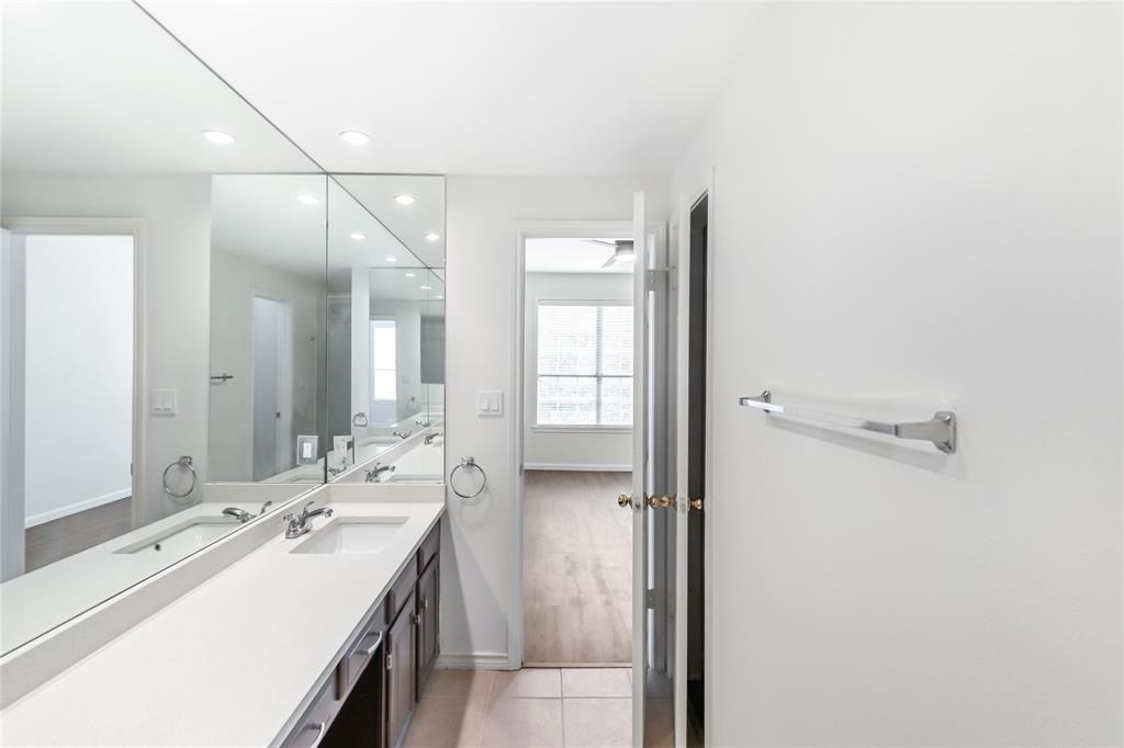 12680 Hillcrest Road, Unit 4101 Dallas, TX 75230 - Photo 30 of 37 Dual sink vanity with white countertop, chrome fixtures, and integrated wall-to-wall mirrors