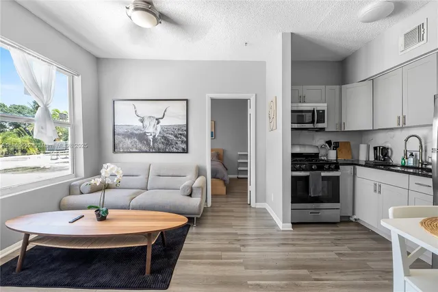 a living room with stainless steel appliances furniture and a wooden floor