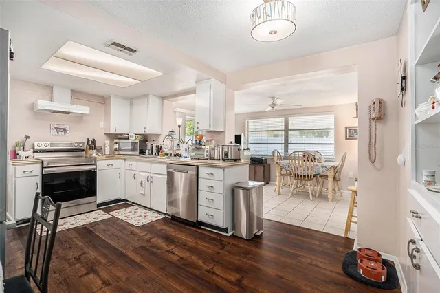 a kitchen with white cabinets and wooden floor