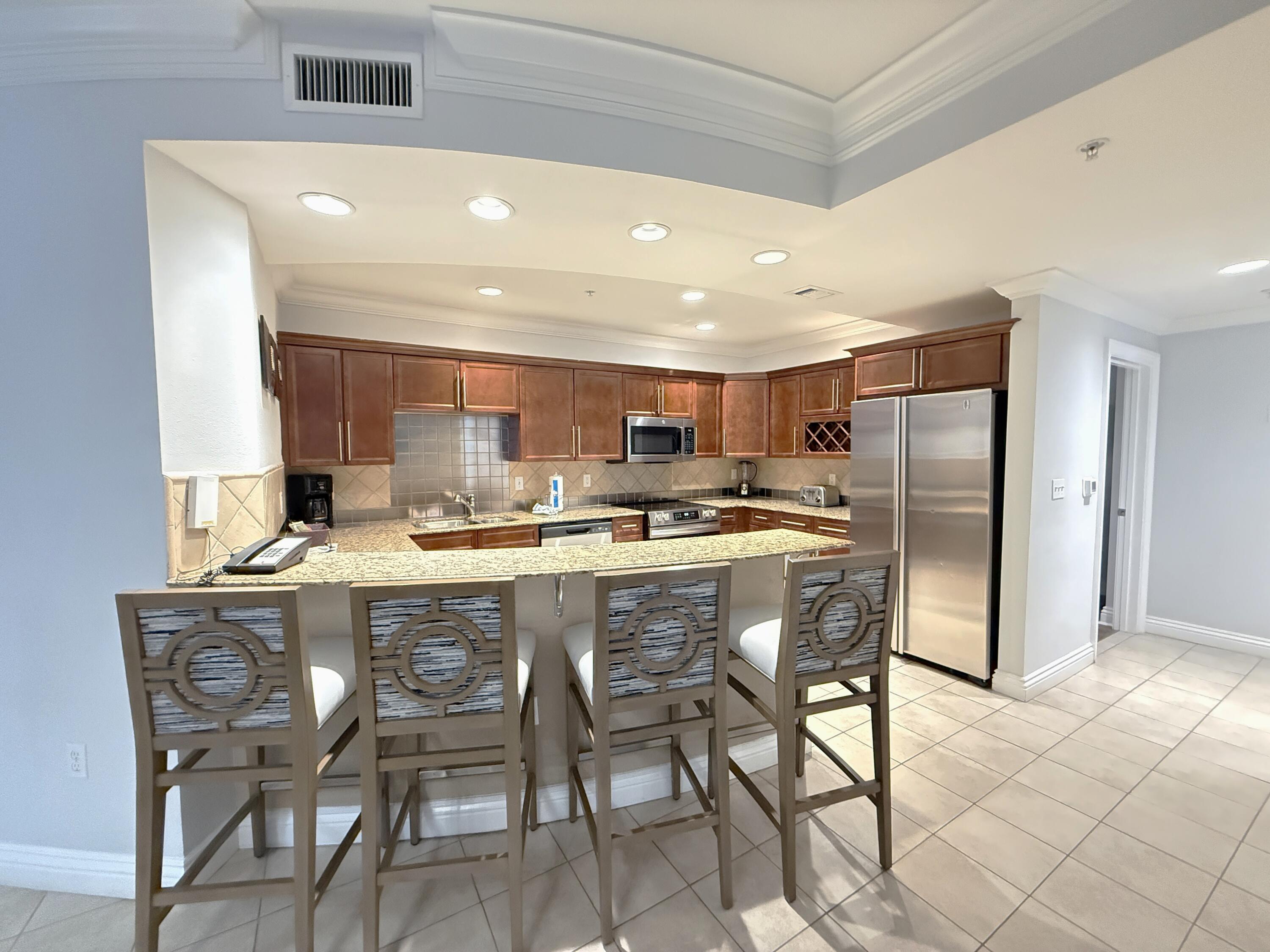 10 Harbor Boulevard, Unit E802B Destin, FL 32541 - Photo 4 of 25 a kitchen with a dining table chairs refrigerator and cabinets