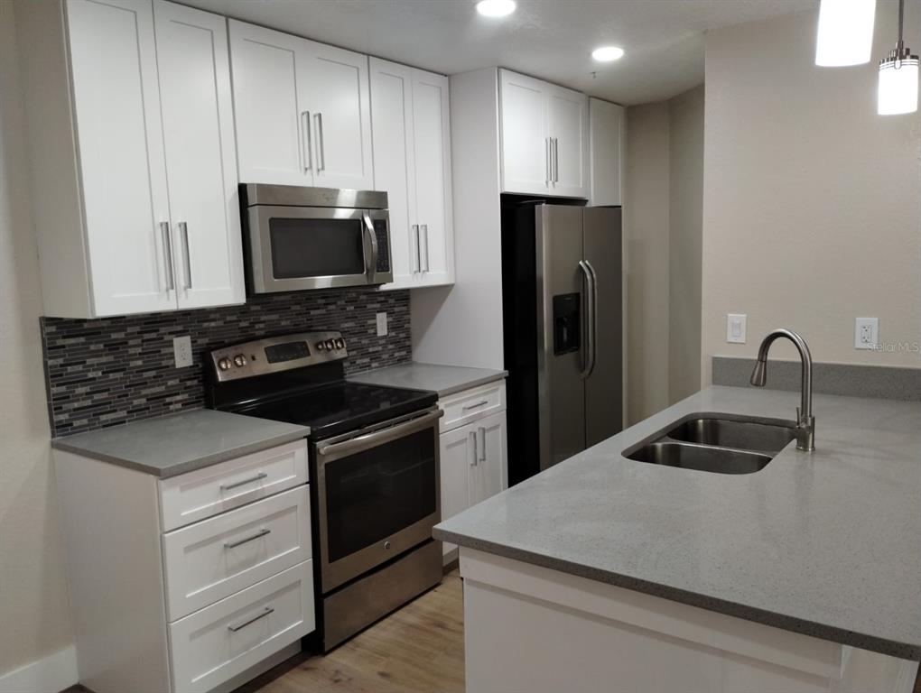 623 Dory Lane, Unit 306 Altamonte Springs, FL 32714 - Photo 13 of 21 a kitchen with kitchen island a sink stainless steel appliances and cabinets
