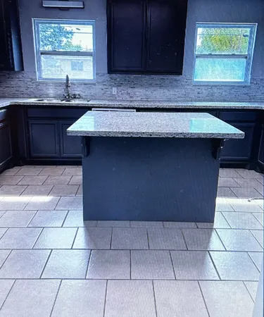 a kitchen with granite countertop a sink a stove a microwave and cabinets