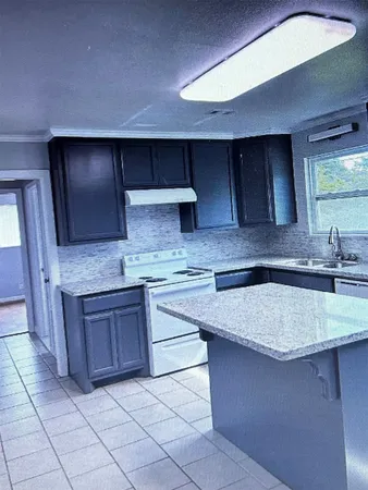 a kitchen with granite countertop a sink and a stove top oven