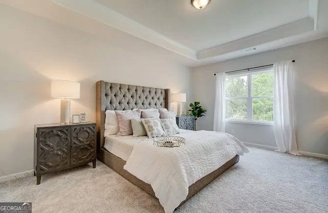 a bed sitting in a spacious bedroom next to a window