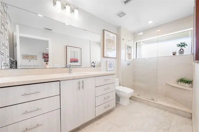 a bathroom with a double vanity sink a toilet and a mirror