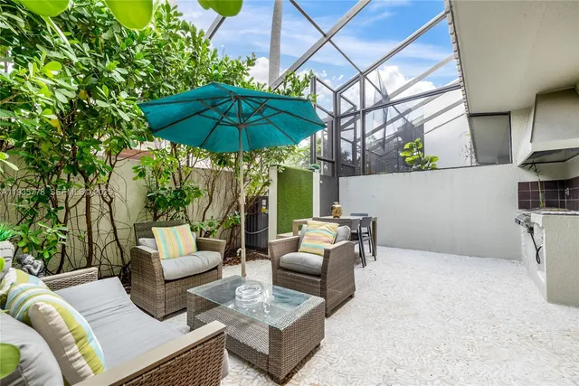 a view of a patio with couches chairs under an umbrella