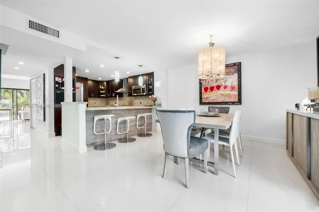 a kitchen with stainless steel appliances kitchen island granite countertop a table chairs and a refrigerator