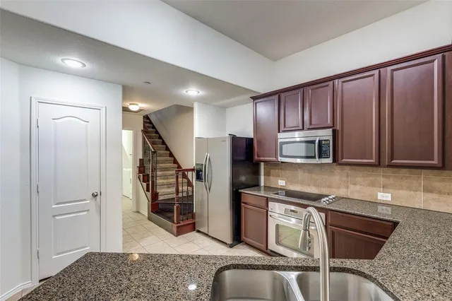 a kitchen with stainless steel appliances granite countertop a refrigerator and a stove top oven