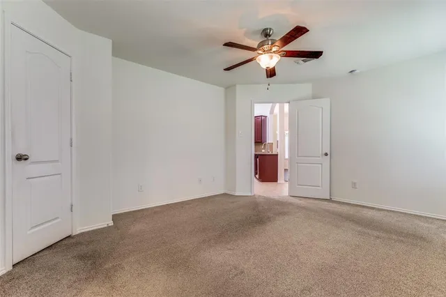 an empty room with ceiling fan and window