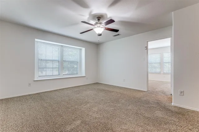 an empty room with windows and fan