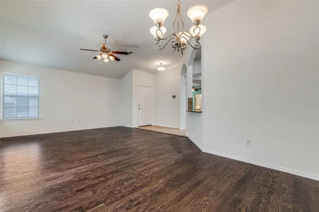 a view of a room with a chandelier fan and wooden floor