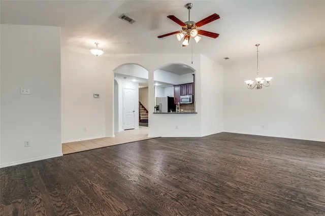 a view of a room with a chandelier fan and wooden floor