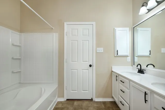 a bathroom with a double vanity sink a mirror and a bathtub