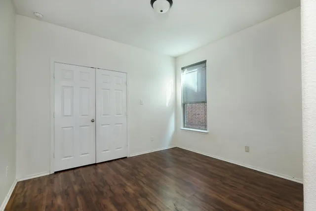 a view of an empty room with wooden floor and closet