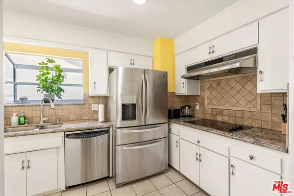 a kitchen with granite countertop white cabinets and white stainless steel appliances